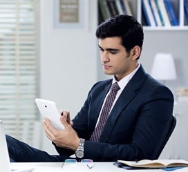a man in a suit sitting on a chair and using a tablet
